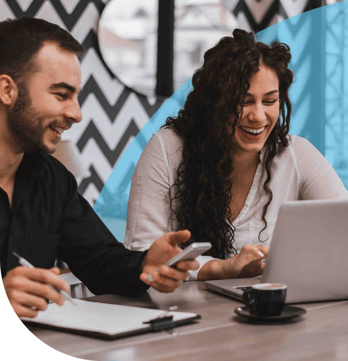 Man and woman smiling at laptop whilst going through some documentation.